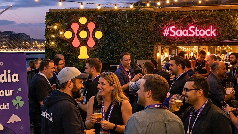 Networking event at SaaStock, with attendees socializing, drinks in hand, and a colorful backdrop featuring #SaaStock.
