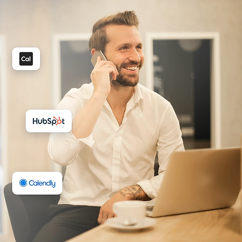 Man on a phone call beside a laptop with Cal, HubSpot, and Calendly logos
