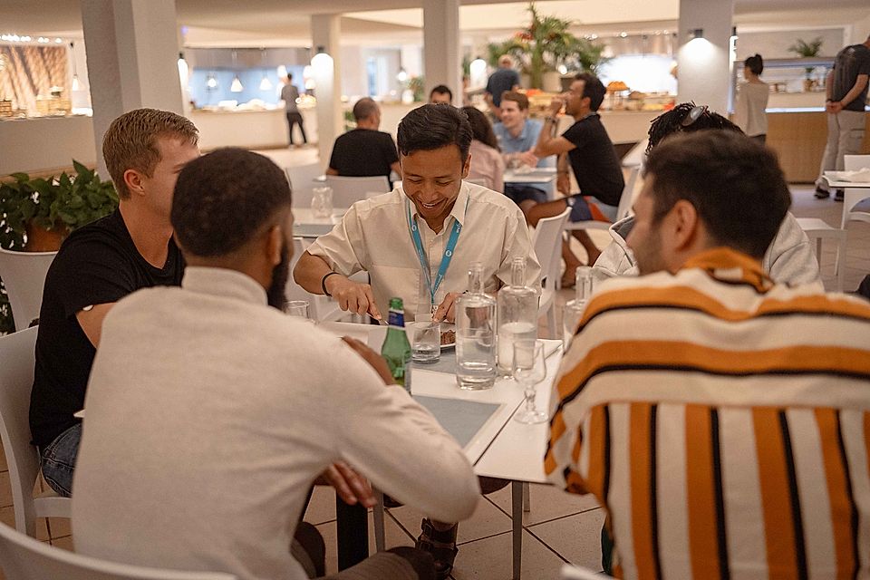 A group of people dining together in a modern restaurant, engaged in conversation and enjoying their meal.