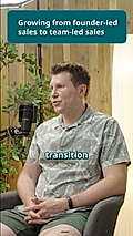 A man in a leafy shirt speaks in an interview setting, discussing sales transition with a microphone in view.