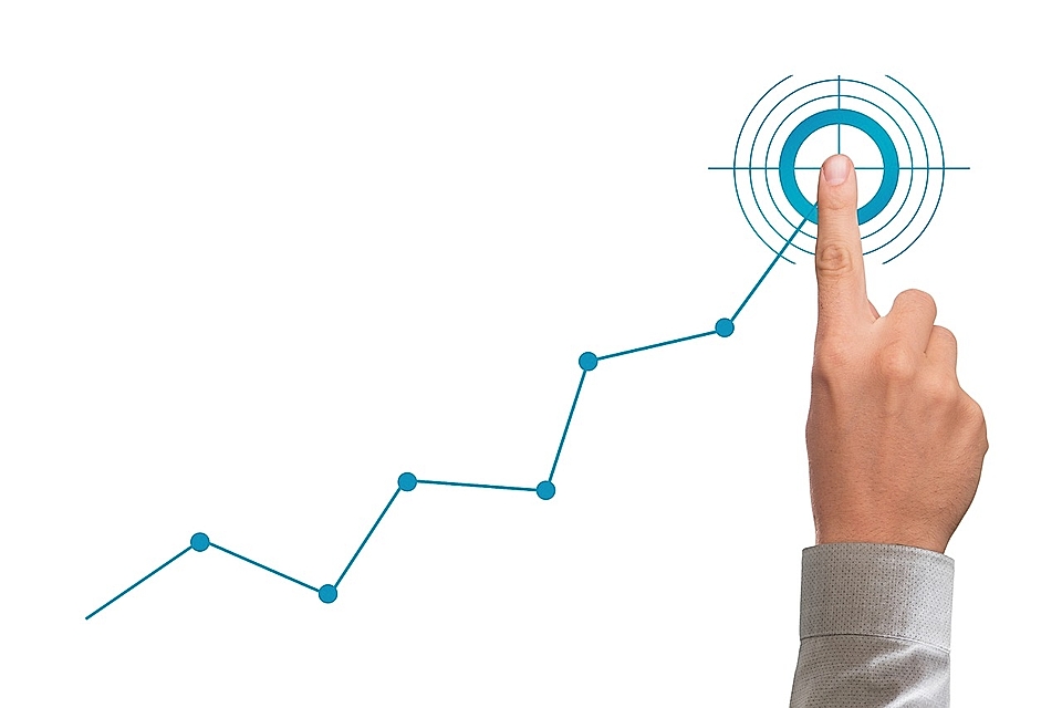 A hand pointing at a target on a rising line graph, symbolizing growth and focus in business performance.