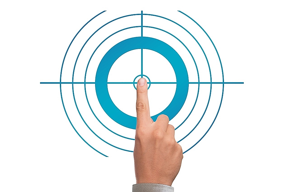 A hand pointing at a circular target with concentric circles, symbolizing focus or precision in marketing.