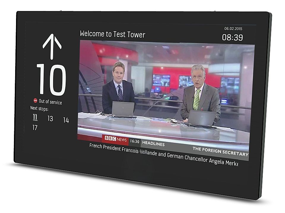 Digital display showing train information and live BBC news broadcast in a modern setting.