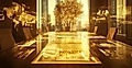 A modern conference room with a golden digital table, views of skyscrapers, and a central tree.