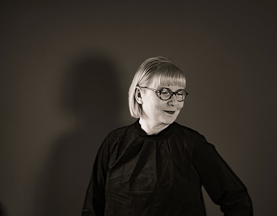 Portrait of a woman with glasses in a black top against a plain background