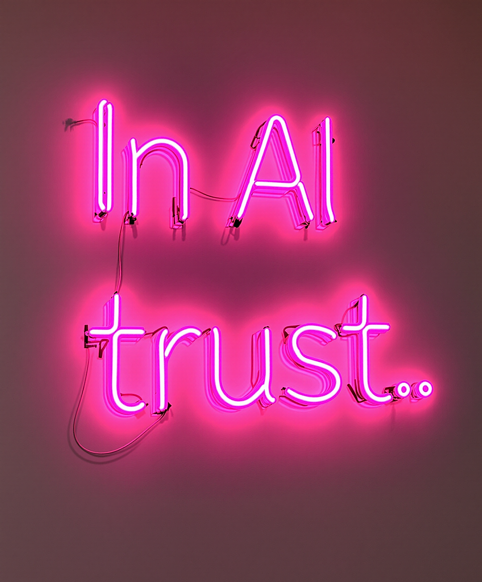 Pink neon sign reading "In AI trust.." on a plain wall.