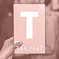 A hand holding a book with a large 'T' and the title 'TARINAT' on the cover, against a blurred background.