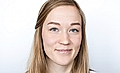 Portrait of a young woman with long blonde hair and blue eyes against a white background, smiling directly at the camera.