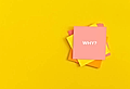 Stack of colorful sticky notes with a prominent pink note displaying the word 'WHY?' on a bright yellow background.