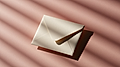 A closed cream envelope resting on a pink surface, with diagonal light and shadow patterns.