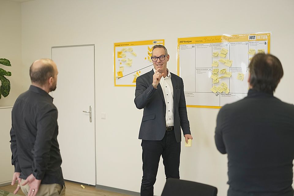 Business meeting with a man presenting beside a wall chart covered in sticky notes