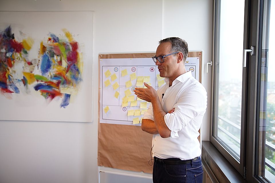 Man presenting beside a planning board with sticky notes in an office