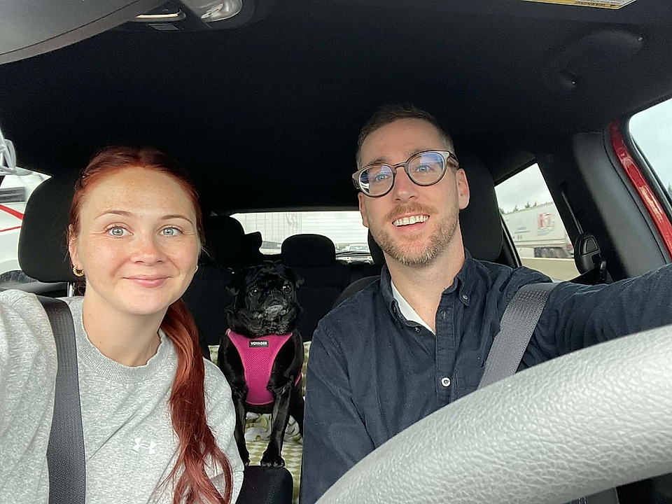 Selfie of two people and a small dog in a car
