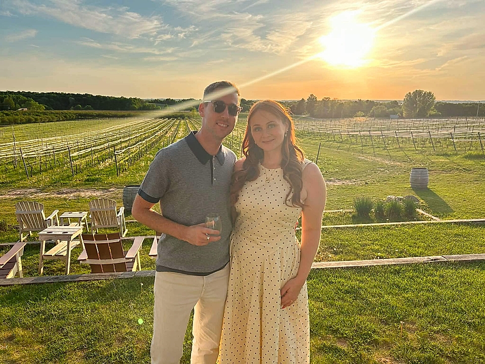 Couple standing outdoors in a vineyard at sunset