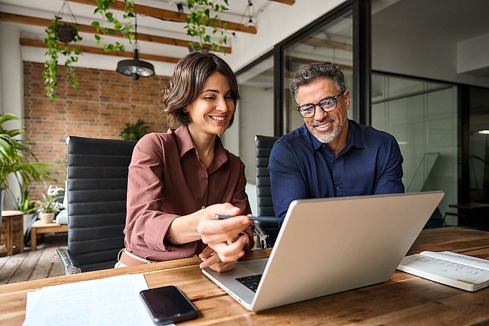 Two coworkers reviewing a laptop in a modern office