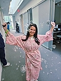 Woman in a pink robe posing in a hallway with bubbles floating around her